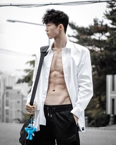 a shirtless man holding a blue pair of scissors in his left hand and looking off into the distance