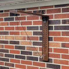 a clock mounted to the side of a brick building next to a metal bar on a wall