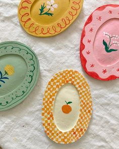 four paper plates with designs on them sitting on a white tablecloth covered table cloth