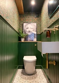 a toilet and sink in a small room with green paneling on the walls above it