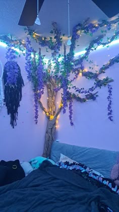 a bedroom with purple flowers on the wall and a tree in the corner next to the bed