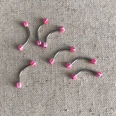 four pink and silver hair pins laying on the ground