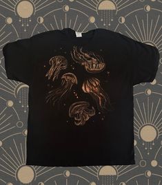 a black t - shirt with an image of jellyfishs in gold on it