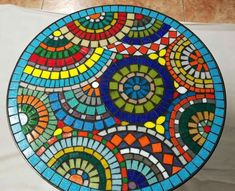 a colorful glass plate sitting on top of a white tablecloth next to a tile floor