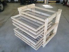 several wooden pallets stacked on top of each other in a garage with two men working behind them