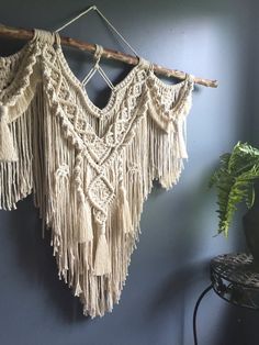 a wall hanging with fringes on it next to a potted plant