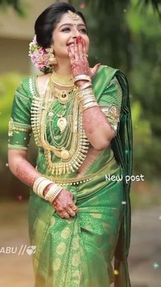 a woman dressed in green and gold with her hands to her mouth, standing outside