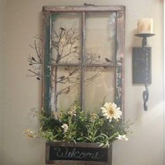 an old window is decorated with flowers and greenery as well as a sign that says welcome