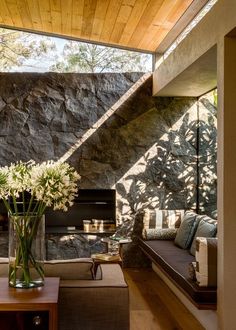 a living room filled with furniture and a fire place next to a stone wall on top of a wooden floor