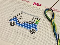 a cross stitch pattern with a blue truck on it and a needle next to it