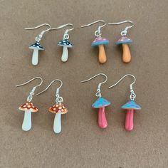 six different colored mushrooms are hanging from earrings