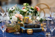 a table topped with books and vases filled with flowers on top of each other