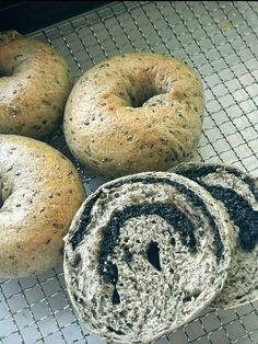 four bagels sitting on top of a cooling rack covered in black and white stuff