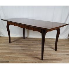 a wooden table sitting on top of a hard wood floor next to a white wall