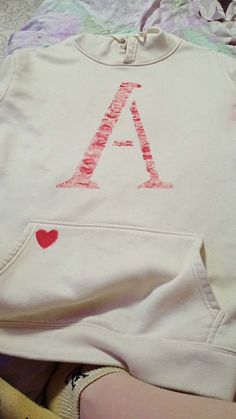 a child's sweatshirt with the letter a on it and a heart drawn in red ink