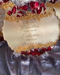 a plate with some writing on it sitting on a cloth covered tablecloth and surrounded by red rose petals