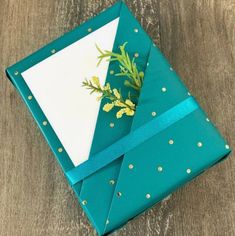 an origami box with green and gold decorations on the lid, tied in a blue ribbon