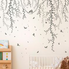 a baby's room with a white crib and tree wall decal on the wall