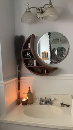 a bathroom sink with a mirror above it next to a candle and some lights on the wall