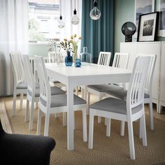 a white table and chairs in a room with blue curtains on the window sill