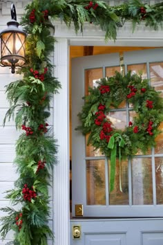 a christmas wreath on the front door of a house with holly and red berries hanging from it