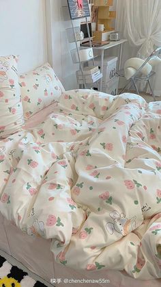 an unmade bed with white sheets and pink flowers on it, in a bedroom