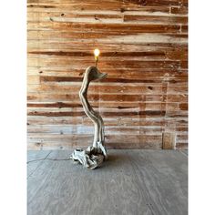 a candle that is sitting on top of a piece of driftwood in front of a wooden wall