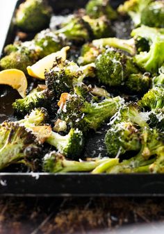 broccoli florets with lemon wedges and parmesan cheese on top