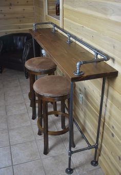 two stools sit at the bar in a small room with wood walls and tile flooring