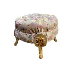 the foot stool is covered in pink and gold fabric with floral designs on it's legs