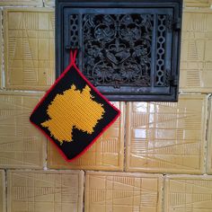 a black and yellow wall hanging next to a metal grate on a tiled wall