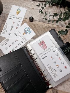 an open planner book sitting on top of a wooden table next to dice and cards