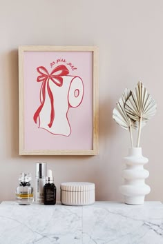 a bathroom with a pink wall and white marble counter top next to an art work