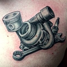 an image of a tattoo on the back of a man's shoulder with a car engine and wrench