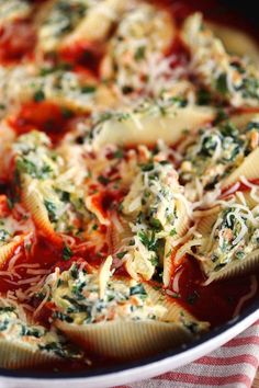 a pasta dish with sauce, cheese and spinach on a red and white checkered cloth