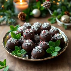 chocolate covered candies with sprinkles on a plate next to christmas greenery