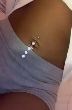 a close up of a woman's stomach wearing a silver ring with pearls on it