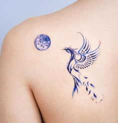 the back of a woman's shoulder with a blue bird and moon tattoo on it