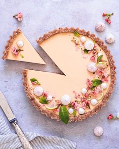 a piece of pie with flowers on it and a knife next to it, surrounded by other food items