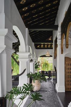 an outdoor walkway with potted plants on either side and arches over the doorways