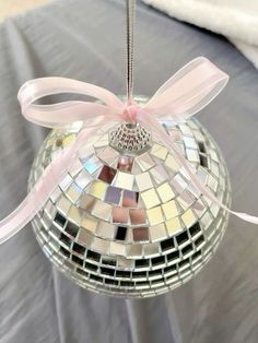 a disco ball ornament with a pink bow hanging from it's side