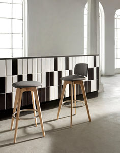 two black and white stools in front of a wall with geometric tiles on it