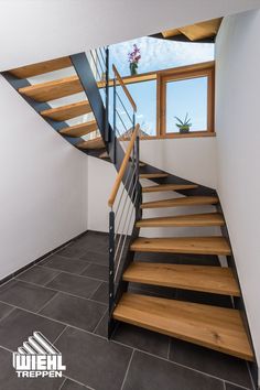 a stair case with wooden treads in a room that has tile flooring and white walls