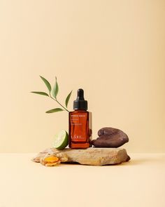 a bottle of essential oil sitting on top of a piece of wood next to a plant