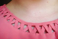 a close up of a woman wearing a pink shirt and necklace with holes in it