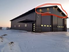 a large black building with an orange ribbon on it's side in the snow