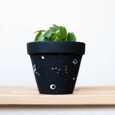 a small potted plant with stars and planets painted on it sitting on a table