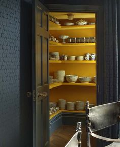 a room with yellow walls and shelves filled with dishes