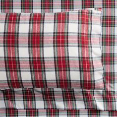 the red and white plaid sheets are neatly folded on top of each other, with two pillows