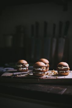 four hamburgers sitting on top of a cutting board